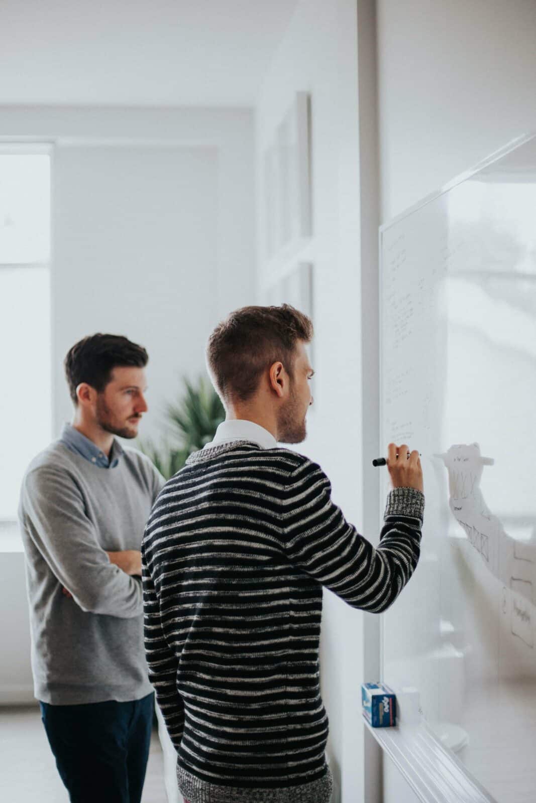 2 teammates writing a digital marketing strategy on a whiteboard